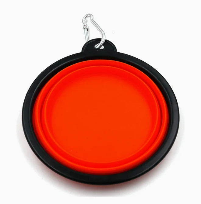 A collapsible pet water bowl with a bright orange interior and a black exterior, featuring a silver carabiner clip at the top, shown on a plain white background.