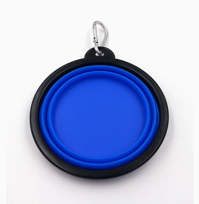 A circular collapsible pet water bowl with a bright blue inner chamber and a black outer rim, attached to a silver metal carabiner clip, shown on a plain white background.