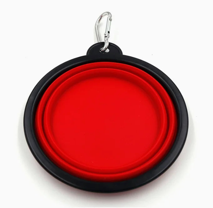 A round collapsible pet bowl with a bright red interior and a black exterior, attached to a silver carabiner clip at the top, shown on a plain white background.